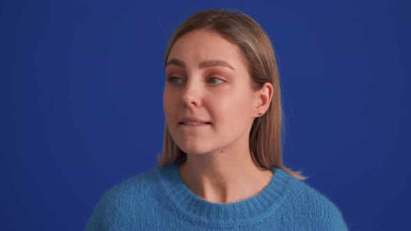 Handsome positive woman wearing blue sweater looking around and showing shh gesture