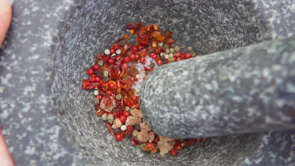 Super Closeup of Heavy Pestle Starting to Grind Mix of Spices and Peppers