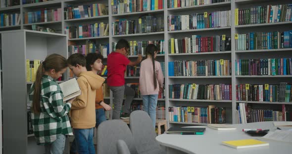 Multinational Kids Look for Books on Shelves in Library