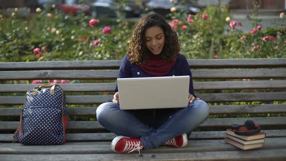 Young Wavy-Haired Woman Communicating With Friends Over Laptop Camera Outdoors