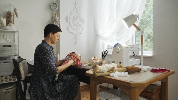 Woman sewing a doll in her atelier alt