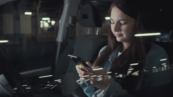 Woman Uses an Application on His Phone While Sitting in the Car in the Parking Lot