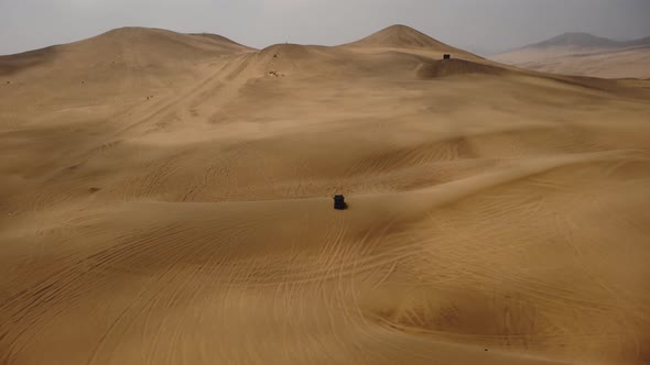 AERIAL - Off-road 4x4 truck in Ica desert sand dunes, Peru, forward tilt down