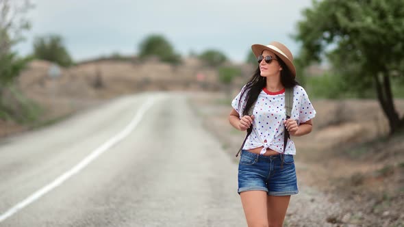 Stylish Woman in Straw Hat and Trendy Sunglasses Walking on Highway