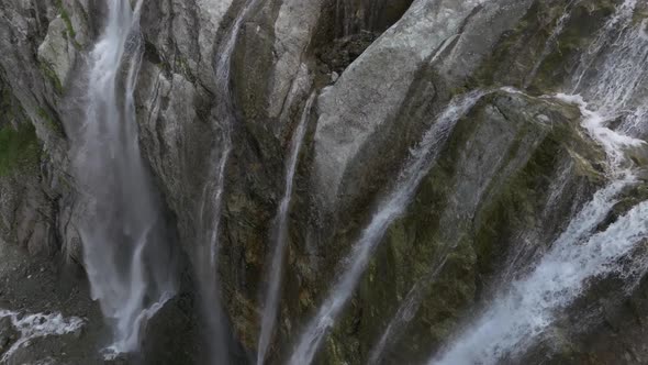 Aerial View Close Up Flight with Mountain Waterfalls Flowing From Glacier Over Rocks