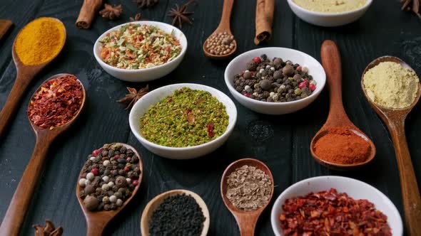 Dry Colorful Spices in Spoons and Bowls with Fresh Seasoning on Dark Background Top View