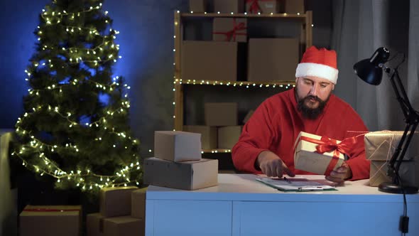 Bearded Hindu Man in a Santa Claus Costume in Home Office Works Delivery Service