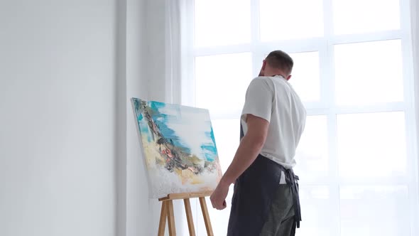 The Artist Paints an Abstract Picture He is Focused on Work Painting on an Easel in His Art Studio