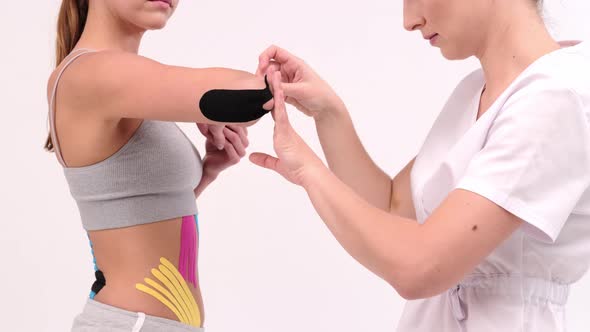 Professional glues tapes on a woman's elbow. Young fit women showing on her elbow