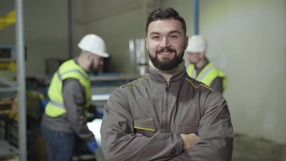 Portrait of Confident Caucasian Man Looking at Camera and Smiling. Foreman with Black Hair and Beard