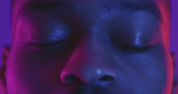 Close Up Shot of African American Man Opening Eyes and Looking Seriously Straight to Camera Neon