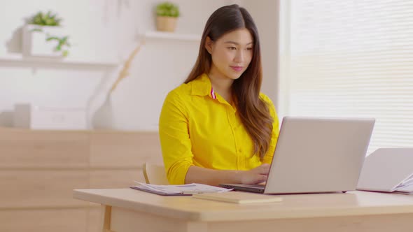 Entrepreneur beautiful business asian young woman wear yellow shirt work online with laptop at home