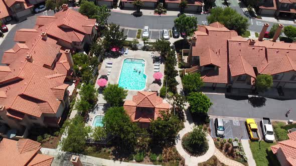 Aerial rotation around a community condo pool with swimmers.