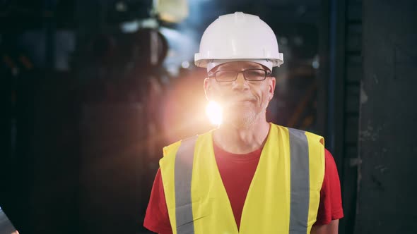 Male Specialist in a Hardhat and a Safety Vest Is Smiling