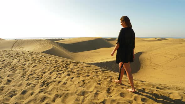 Elegant Model in Black Coverup Walking Barefeet with a View of Sand Dunes