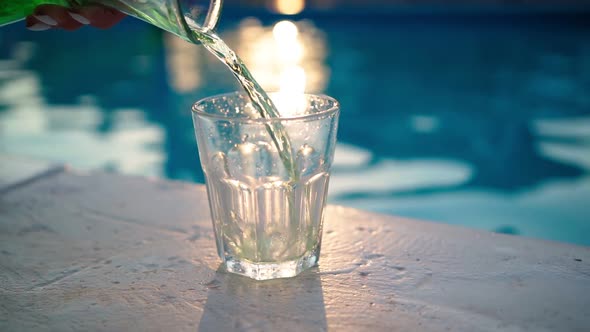 Green Refreshing Drink is Poured From Bottle Into Glass Backdrop Swimming Pool