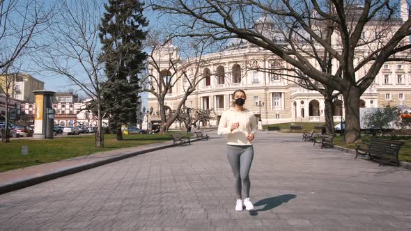 Beautiful Young and Fit Woman Running and Jogging Alone in City Center Wearing Protective Face Mask