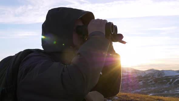 A young man in army looks through binoculars.