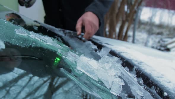 Senior Person Hand Removes Ice From Automobile Windshield