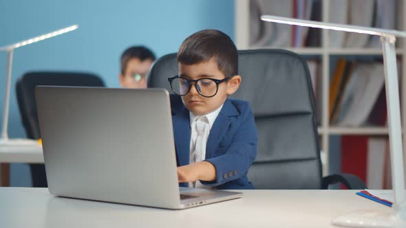 Adorable Preschool Child Working on Laptop at Table in Suit and Glasses