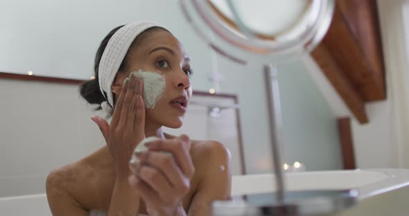 Mixed race woman taking a bath applying beauty face mask