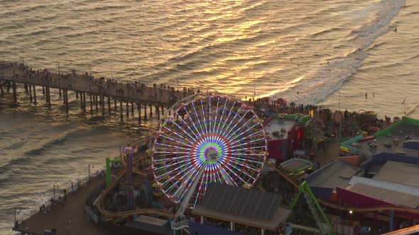 AERIAL: Coming Down on Santa Monica Pier Ferris Wheel, Los Angeles at Beautiful Sunset with Tourists