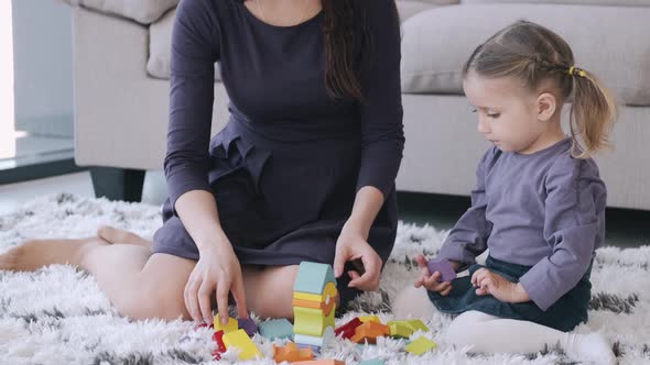 Beautiful Mother and Toddler Daughter Are Playing Construction Toys Together in a Room