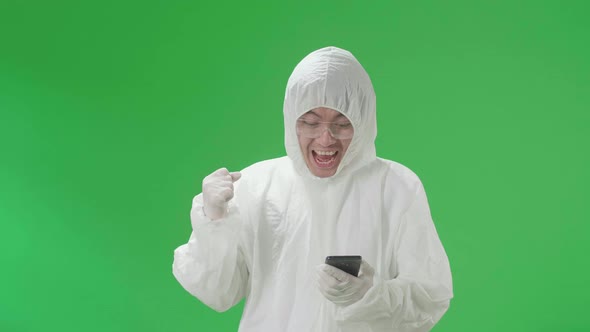 Man Wear Protective Uniform Ppe And Use Mobile Phone Then Celebrating In The Green Screen Studio