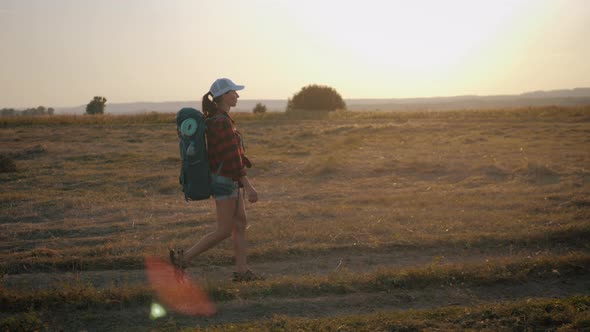 Young Hiker Woman with a Backpack at Sunset