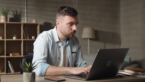 Young Businessman Working on Online Project on Computer at Modern Living Room or Office Enjoying