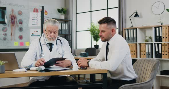 Man which Visiting His Respected Professional Bearded Doctor in Medical Office and telling