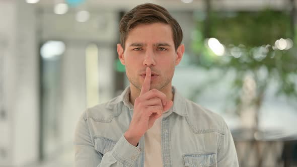Portrait of Creative Young Man Showing Quiet Sign Finger on Lips