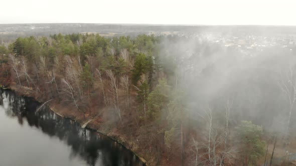 Charming Misty Forest on the Shore of a Reservoir in Autumn. Flying Through the Haze