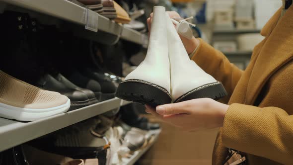 A Middleaged Woman Chooses Warm Shoes in the Store