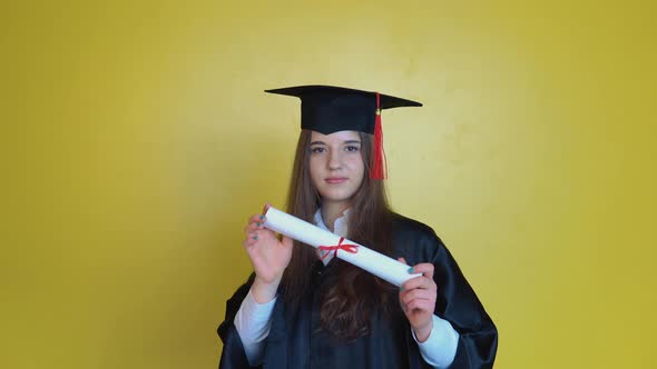 Caucasian Young Woman Student Shows Her Graduating Diploma While Staying in Front of Cameraon Yellow