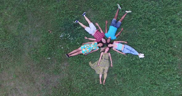 Young happy friends forming a star shape lying in grass