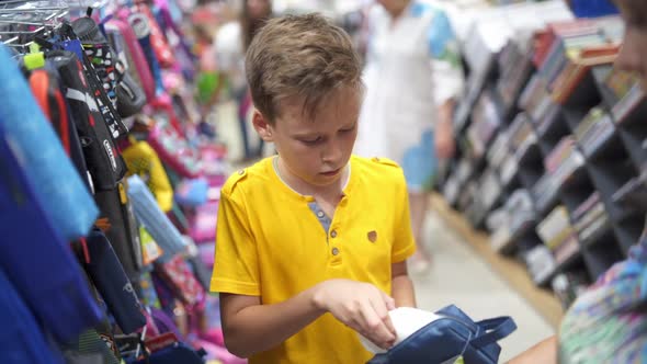 Boy choosing school stationery. Young boy choosing school supplies in stationery shop