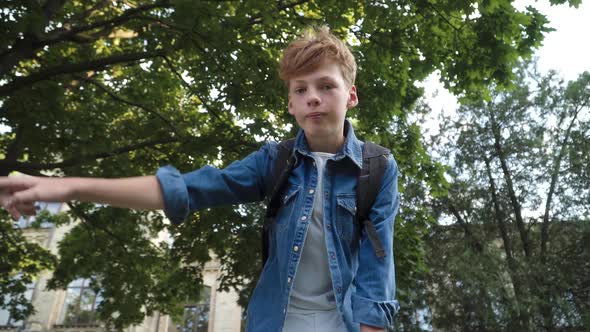 Bottom View of Aggressive Redhead Caucasian Boy Talking and Pointing at Camera. Schoolboy Aggressor