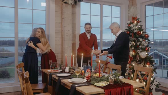 Grandparents Hug with Their Children on Christmas Eve at the Festive Table