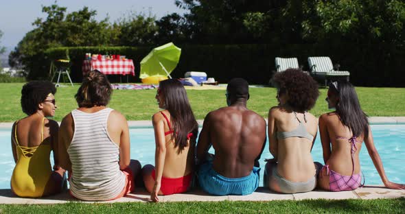 Diverse group of friends sitting in a row looking at the camera at a pool party