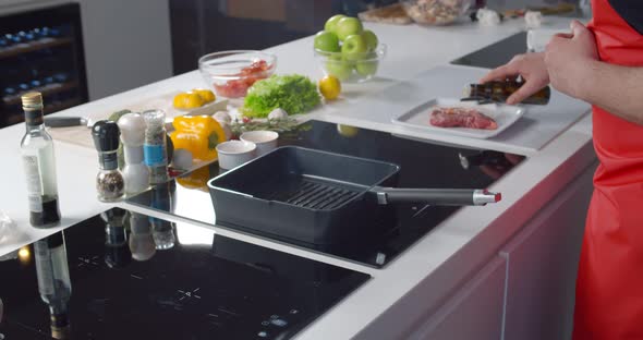 Close Up of Man Chef Pouring Oil on Hot Grill Frying Pan Cooking Steak