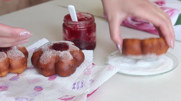 A Woman Dips A Donut In Powdered Sugar. Puts Jam On Donuts. Prepares Donuts In The Form Of A Flower