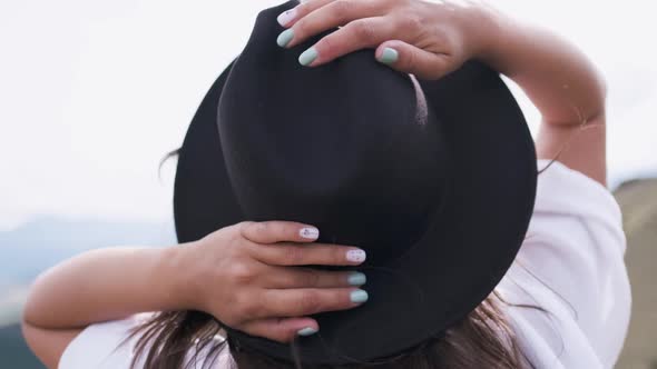 Attractive Brunette in a Hat and White Shirt Is Enjoying Nature in the Mountains. Hat and Hair