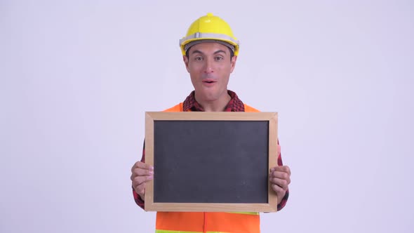 Young Happy Hispanic Man Construction Worker Holding Blackboard and Looking Surprised