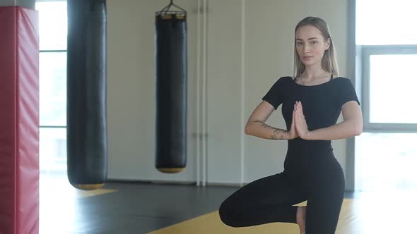 woman meditates in a balance pose in the training room. girl takes a breath.