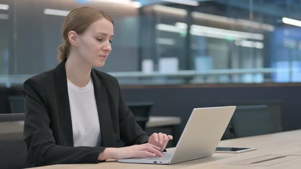 Businesswoman with Laptop Pointing Towards Camera