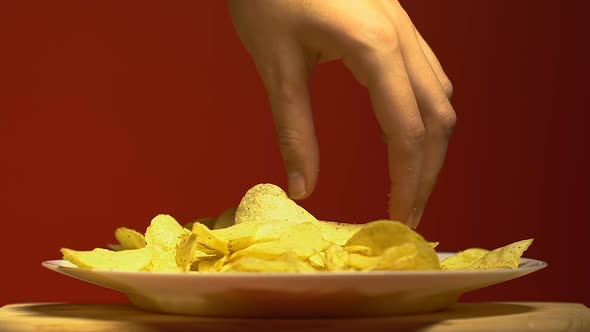 Womans Hand Slowly Taking One Piece of Chips, Junk Food Addiction, Close Up