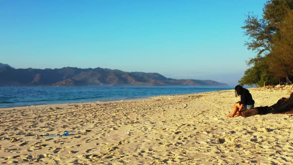 Woman sunbathes on beautiful sea view beach lifestyle by blue ocean and bright sandy background of t