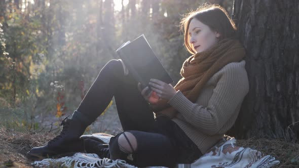 Happy Nostalgic Woman Traveler Reading Book, Relaxing and Looking at Sunset in Autumn Forest