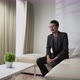 Asian man make a video call, interview, or conference sitting on a sofa with white concept room - VideoHive Item for Sale